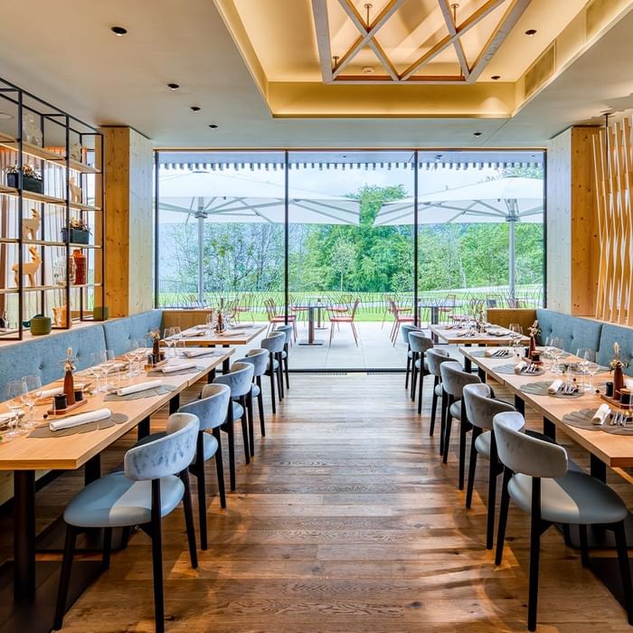 Restaurant Stäffa interior with set tables and garden view at Falkensteiner Hotel Montafon