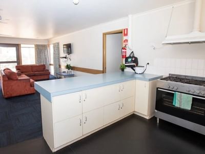 Open-plan living space with kitchen, oven, and red couches near a glass door.