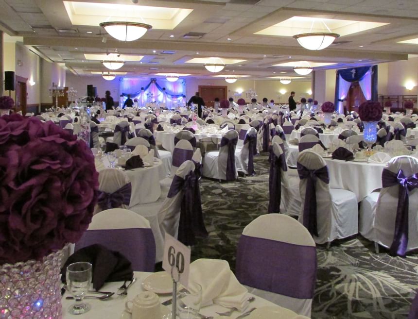 Purple-themed banquet table set-up with flower decor and culinary in ballroom at The Glenmore Inn & Convention Centre
