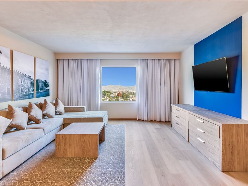 Living area with TV, coffee table, comfy couch and window with city view in Prime Suite at Fiesta Inn