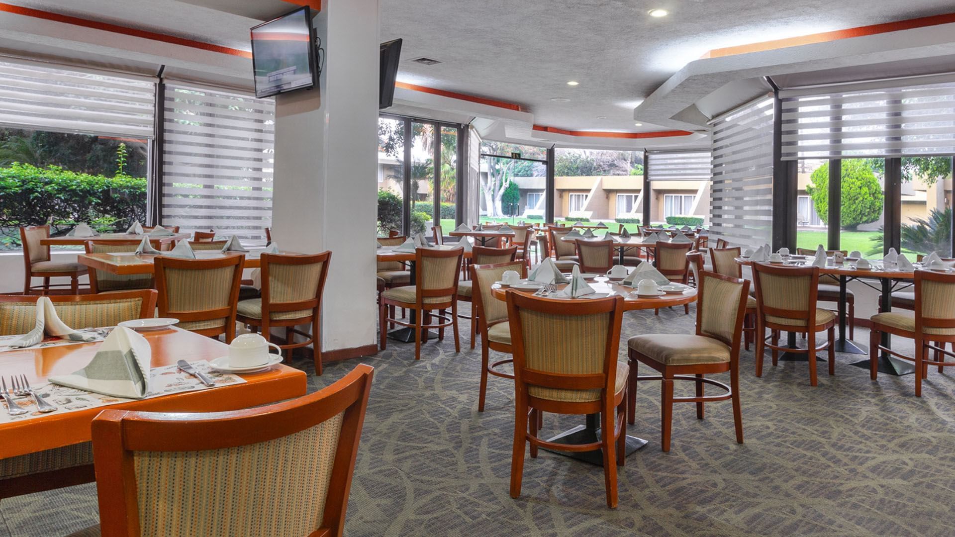 La Huerta restaurant with wooden chairs and green garden views via windows at Camino Real Guadalajara