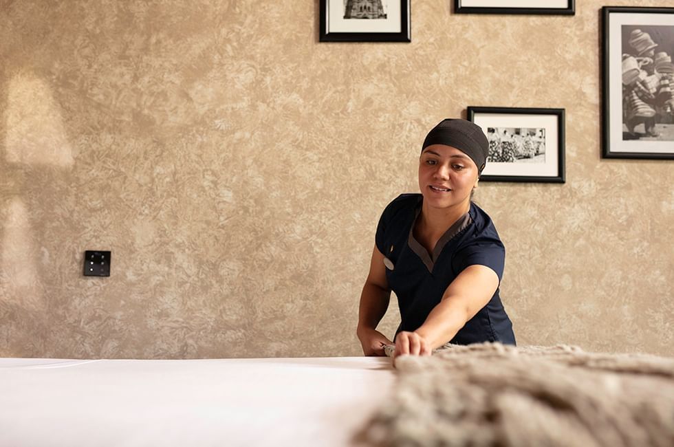 Staff member making bed in room at Live Aqua Resorts and Residence Club