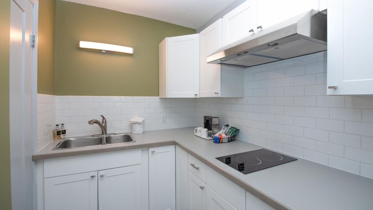 Kitchenette at Coast Red Deer Hotel with sink, stovetop and cabinets