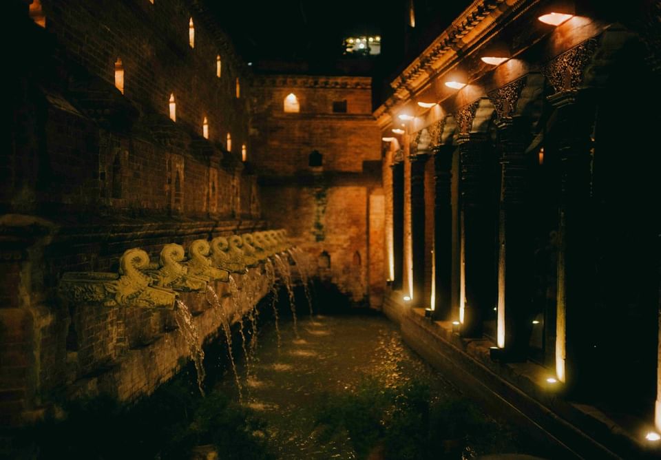 Dimly lit ancient structure featuring ornate stone fountains and illuminated brick walls at The Dwarika’s Hotels and Resorts