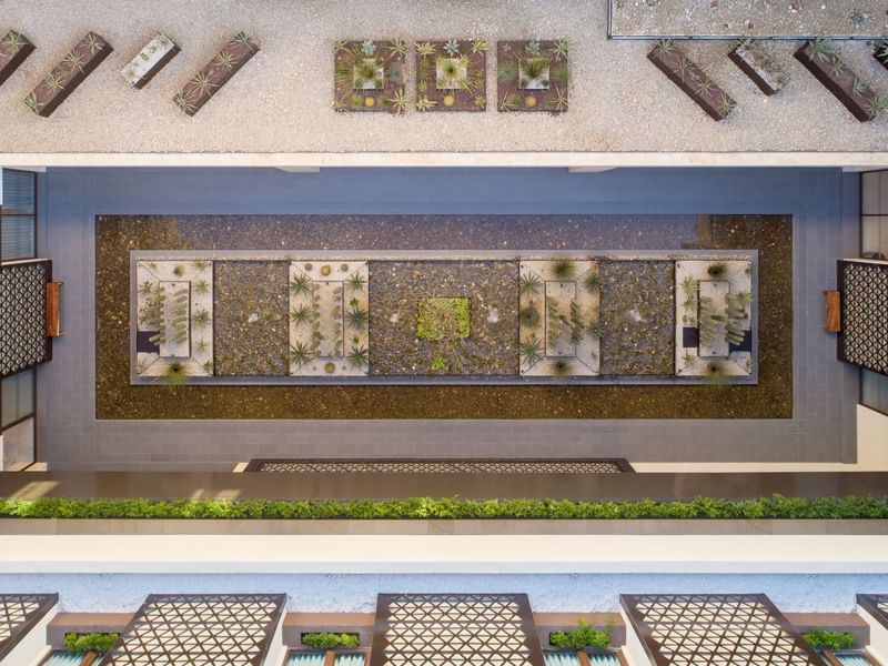 Aerial view of Patio Central with succulent-filled planters, gravel, and surrounding water at Grand Fiesta Americana