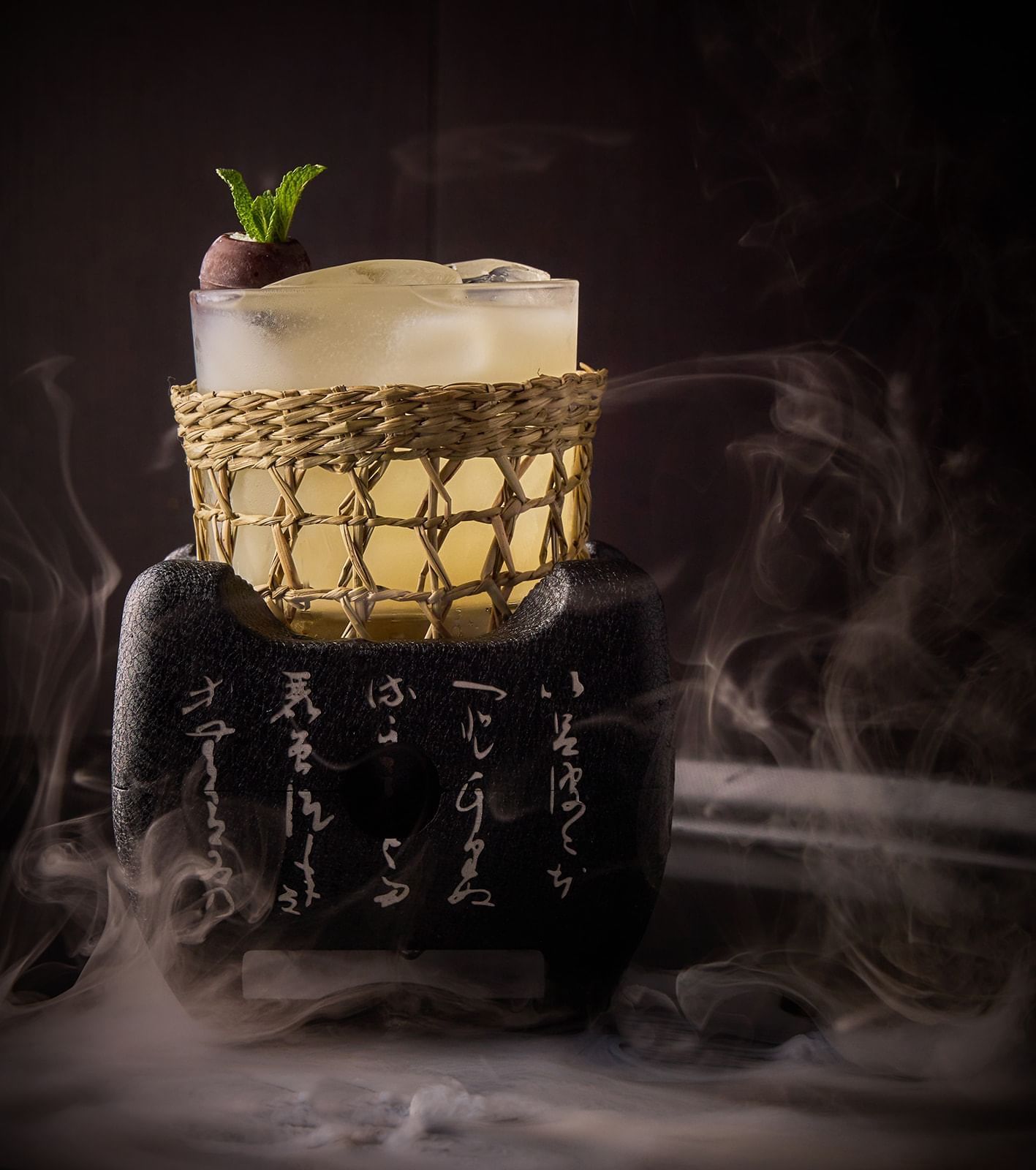 An exquisitely presented cocktail in a woven glass holder on a smoky, inscribed base at The Londoner Hotel's bar