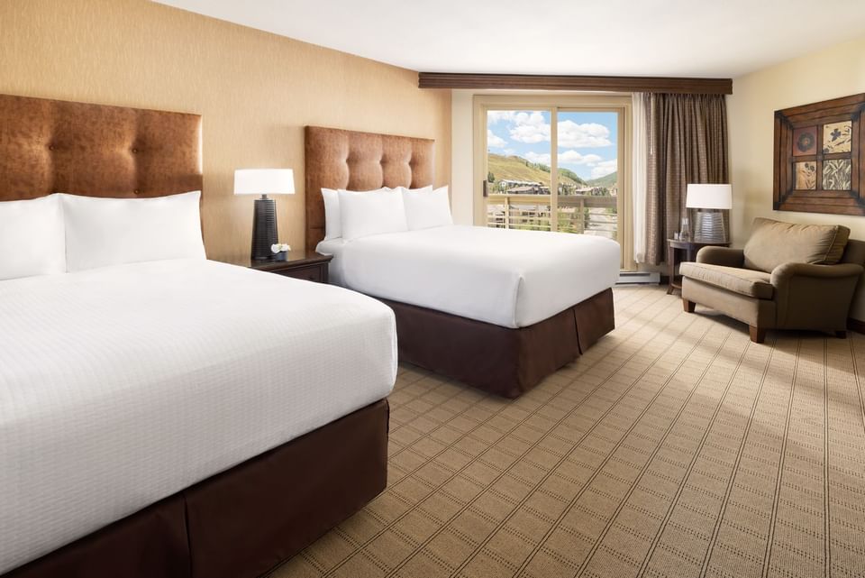 Two beds, a chair, and a balcony with a mountain view at Elevation Resort and Spa