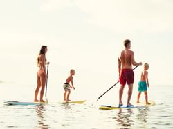 A family on surfboards in the sea near ICONA Hotel Windrift