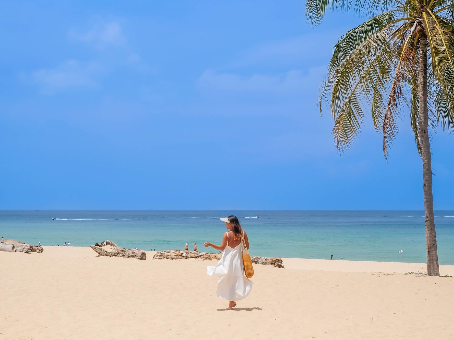 A woman is walking on the white sand Karon Beach with turquoise clear blue sea