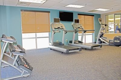 The spacious and clean fitness center at Hotel Topeka features treadmills, free weights, and ellipticals.