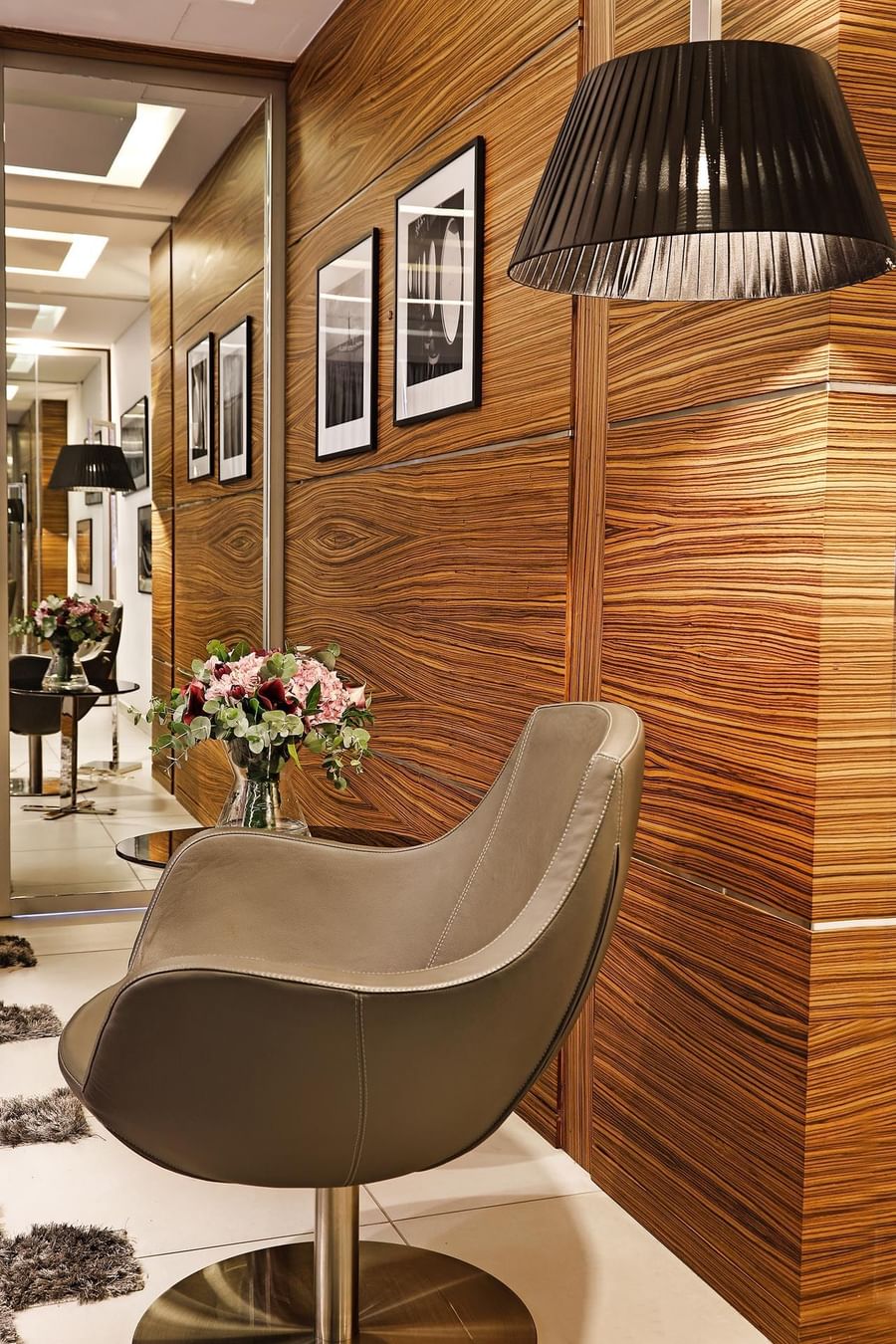 Leather chair by a floral bouquet near a wood-paneled wall under framed art in Executive Suite at Warwick Stone 55 - Beirut