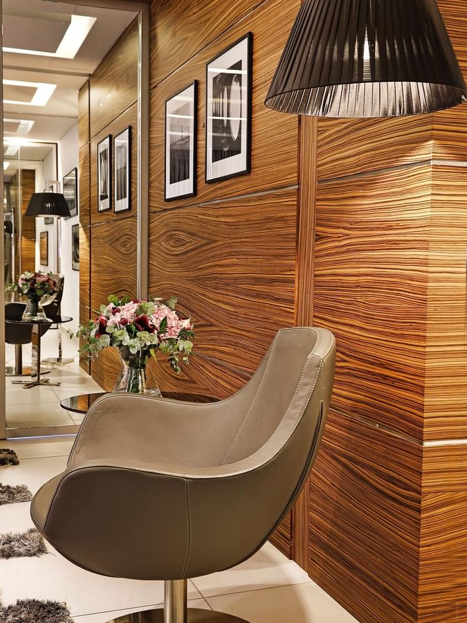 Leather chair by a floral bouquet near a wood-paneled wall under framed art in Executive Suite at Warwick Stone 55 - Beirut