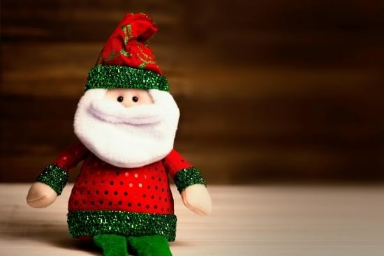 A toy Santa in a red and green outfit. 