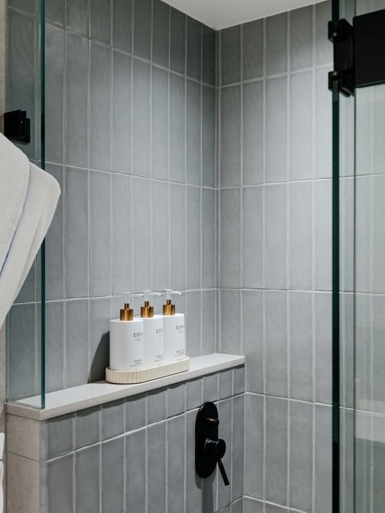 Ocean View Terrace King at Elysium Manly with ESPA amenities on a shelf by a glass shower door under a white robe on a hook