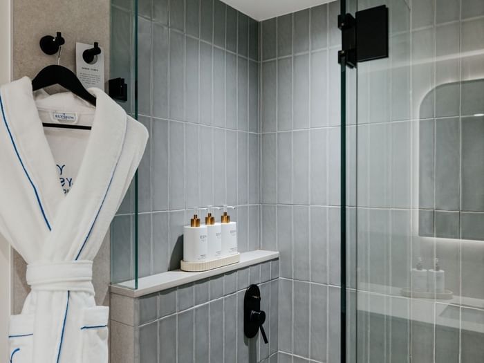 Ocean View Terrace King at Elysium Manly with ESPA amenities on a shelf by a glass shower door under a white robe on a hook