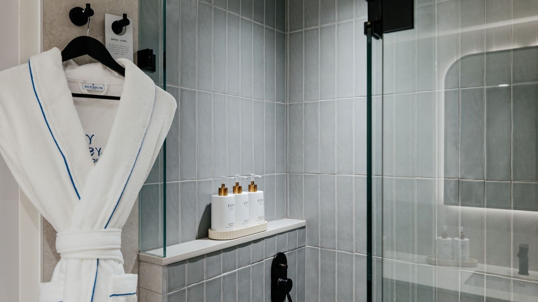 Ocean View Terrace King at Elysium Manly with ESPA amenities on a shelf by a glass shower door under a white robe on a hook