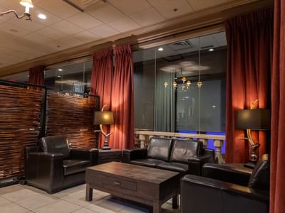 Three black leather couches surround a coffee table in a lounge area at Carriage House Hotel & Conference Centre.