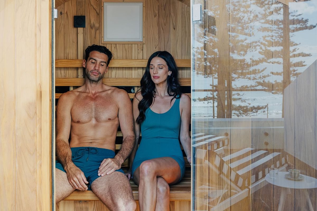 Couple relaxing on wooden benches inside a barrel sauna at Elysium Hotels, the best 5-star hotels in New South Wales