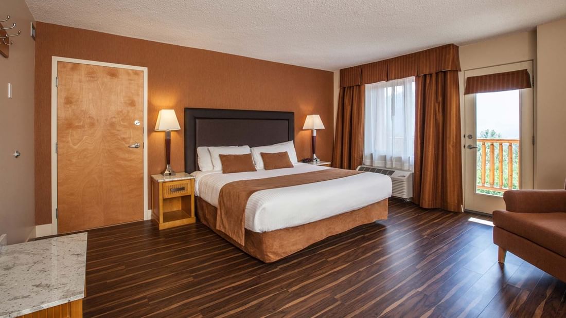 King bed in hotel room with wood floors, with balcony