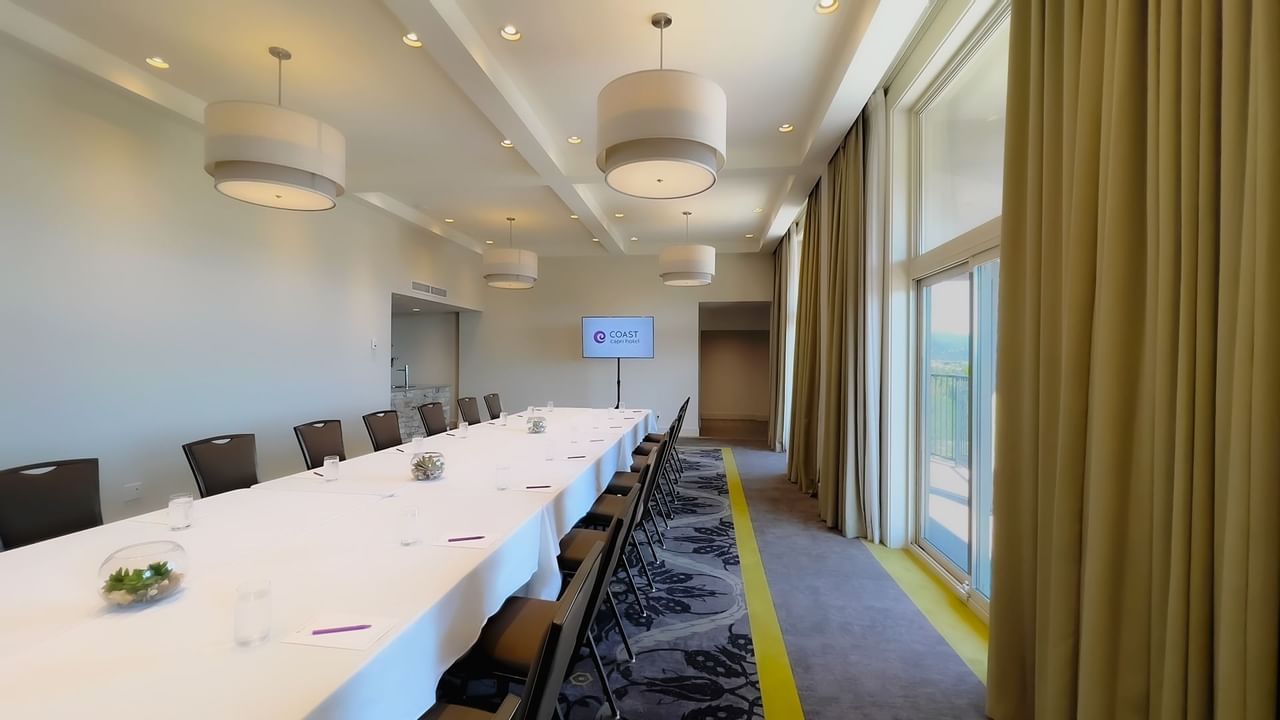 Long boardroom table set with water, pens and chairs