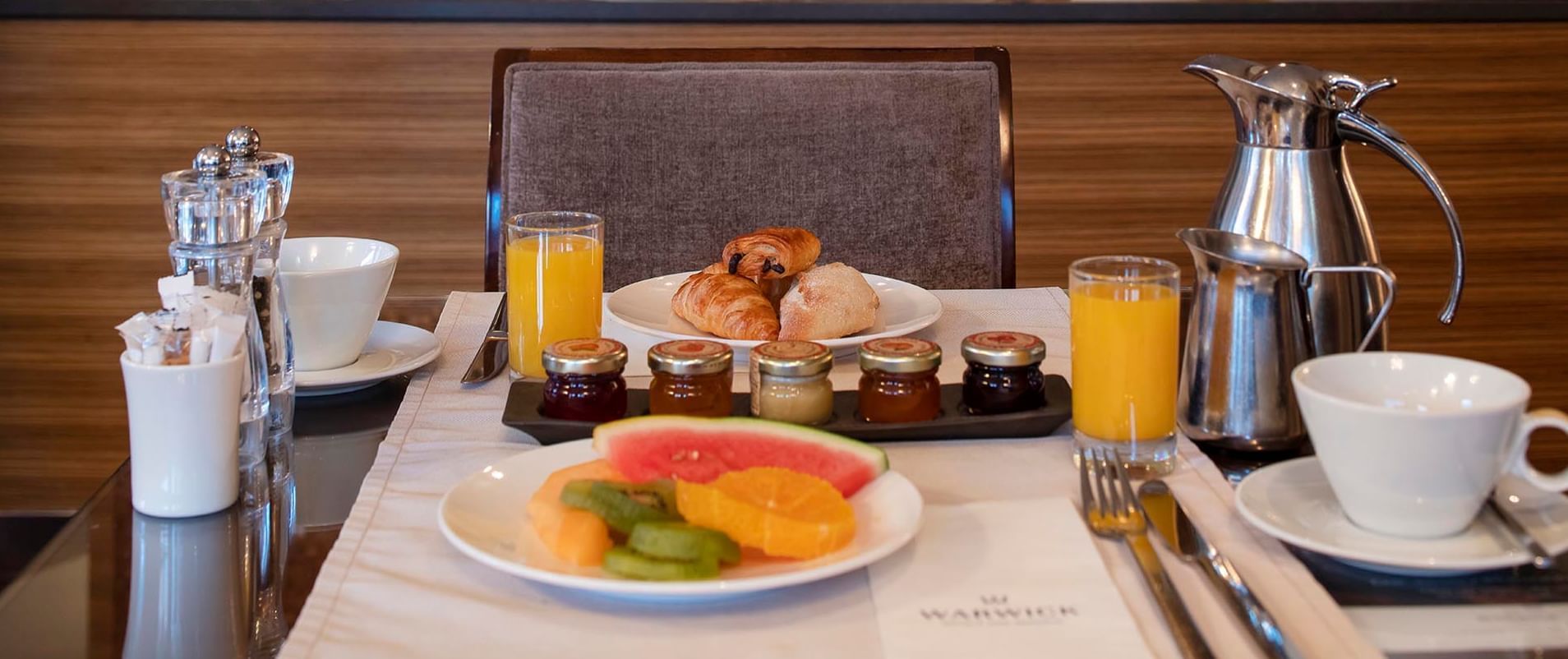 Well-set breakfast table featuring fresh fruit, croissants, & orange juice at Téséo Restaurant
