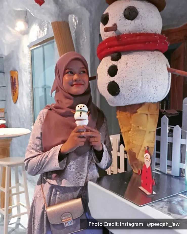A woman was taking a picture with a snowman figurine at Ice Cafe Penang - Lexis Suites Penang