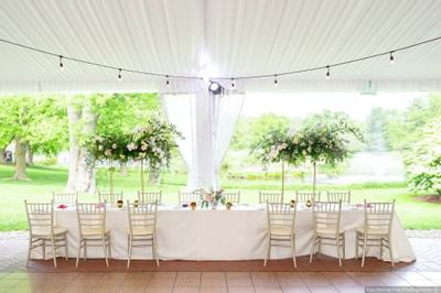 Elegant outdoor tent reception with, gold chiavari chairs, and floral centerpieces at Aramark Chauncey Conference Center