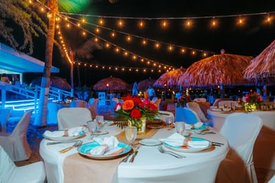Lights & tables arranged outdoors by the shore at night in Passions on the Beach