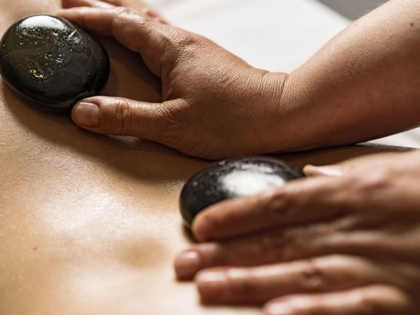 Guest receiving a hot stone massage at Warwick Le Crystal