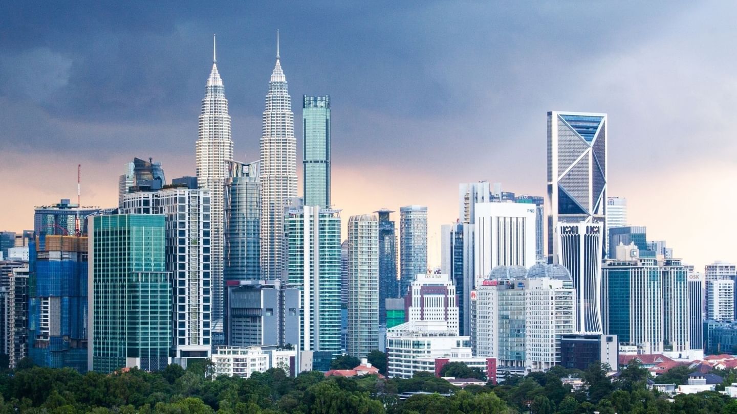 Skyline of Kuala Lumpur with modern skyscrapers and Twin Petronas Towers under a cloudy sky near Sunway Velocity Hotel