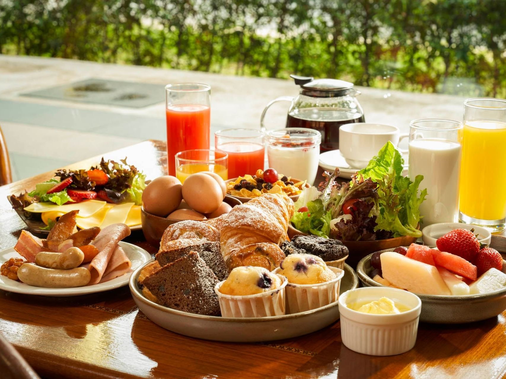 Luxurious breakfast spread with meats, pastries, salad, fruits, and drinks on a table at Crystal Cafe, Orchard Grand Court