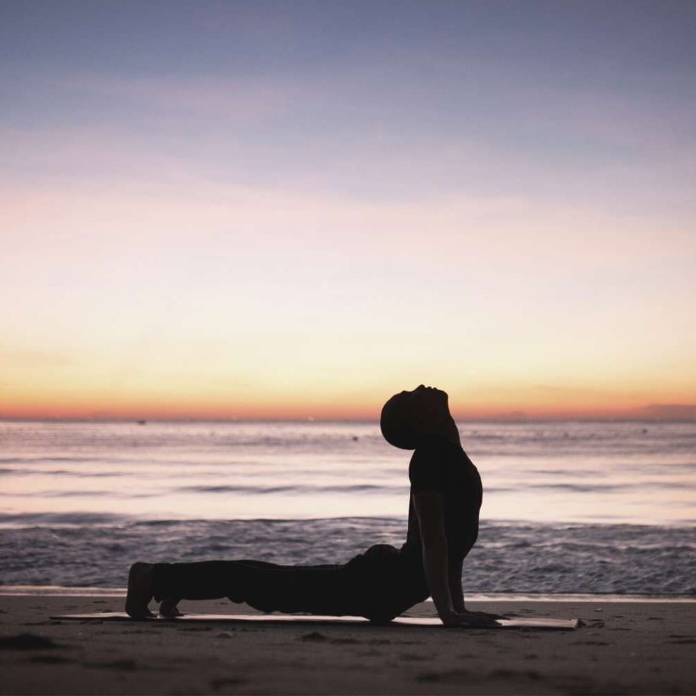Man doing yoga on the beach at sunset near Waikiki Resort Hotel by Sono
