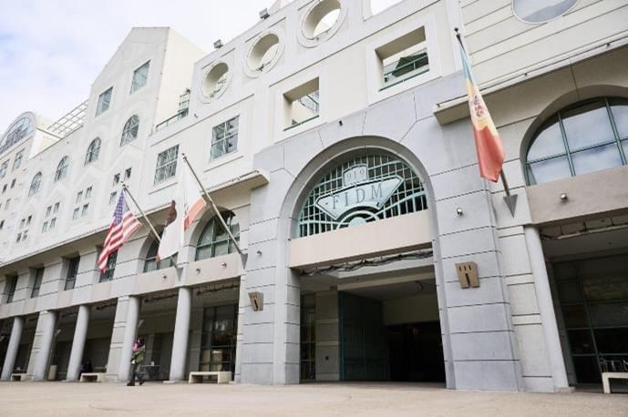 A white building with a large arched doorway and flags flying in front of it.