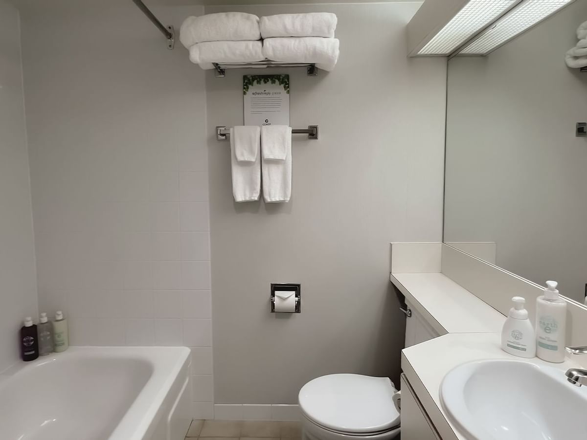 Bathroom with towels, toilet, mirror, bath and sink