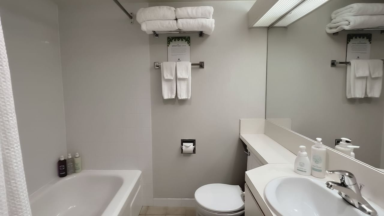 Bathroom with towels, toilet, mirror, bath and sink