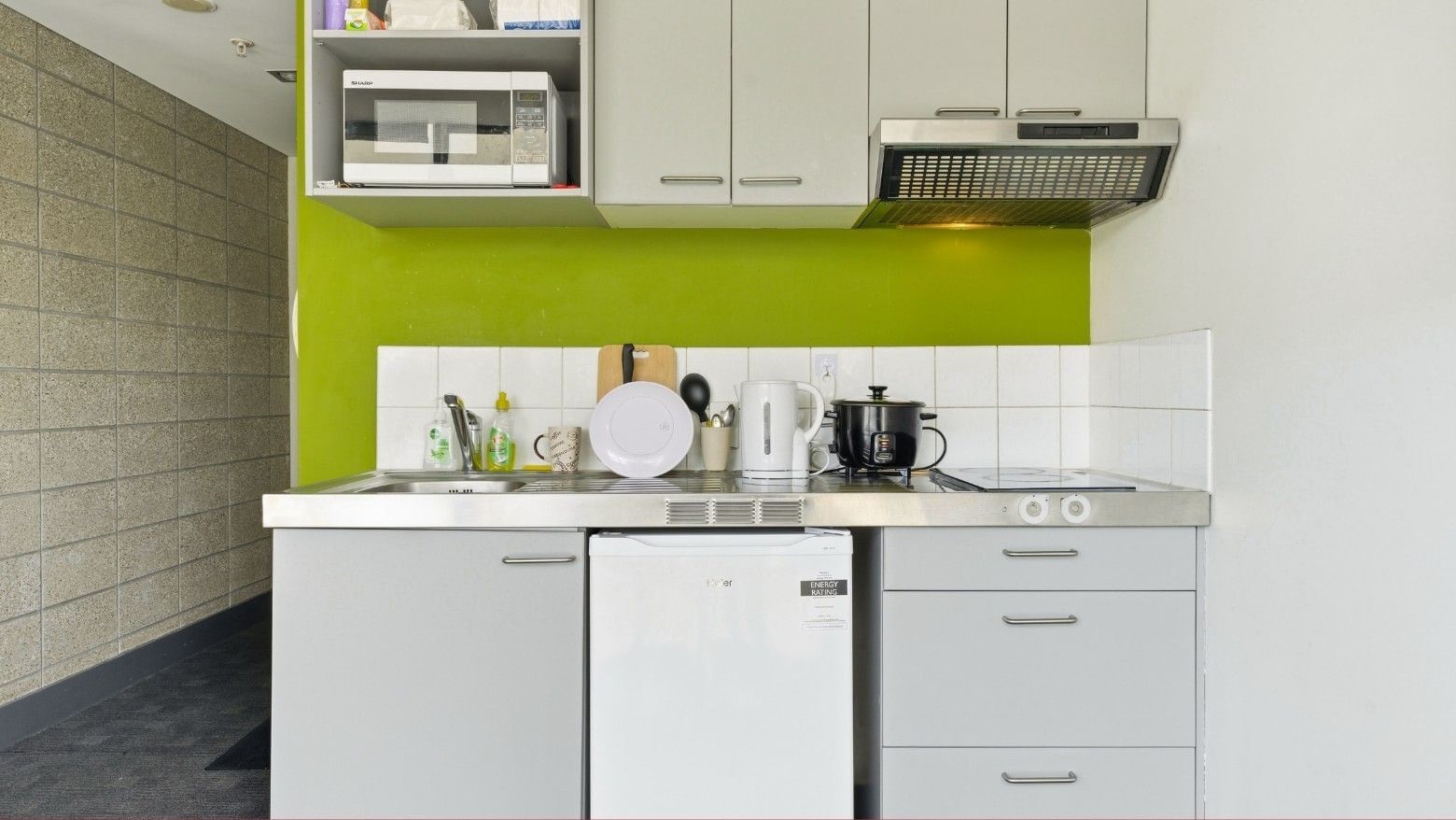 Kitchen area with microwave, stove, sink, and refrigerator at Student Living Auckland - Beach.
