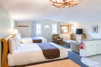 Room with two beds, nightstand & living room at Alpenhof Lodge