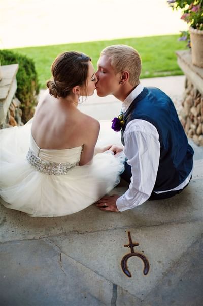 Newlywed couple shares a kiss on stone steps, the bride in a gown and the groom at Blair Hotels