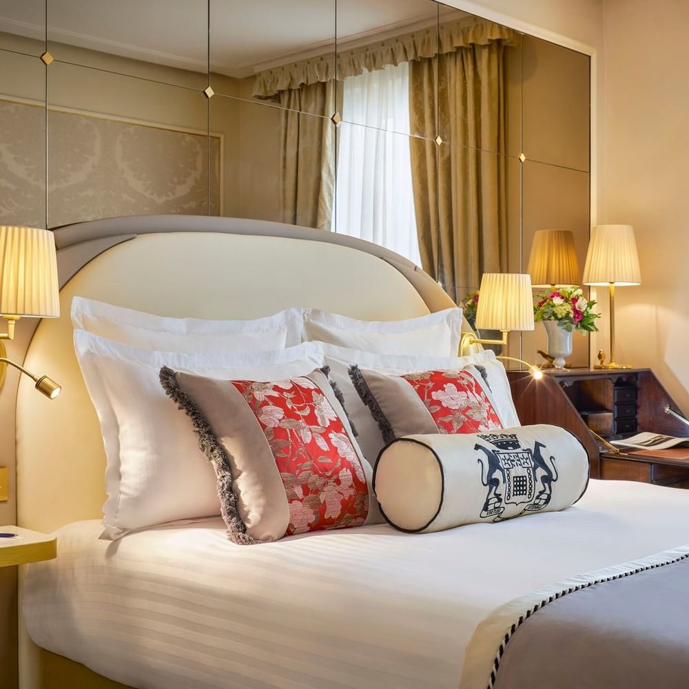 Élégante chambre double supérieure avec un grand lit, des oreillers à motifs floraux et un bureau raffiné à l'Hôtel Westminster - Paris.