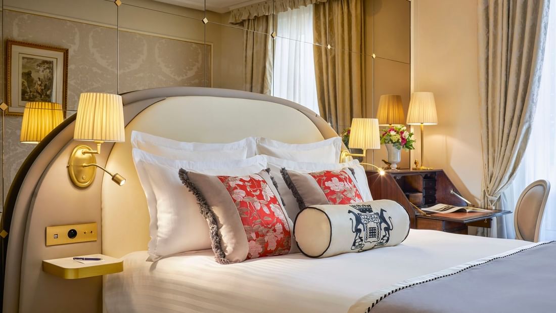 Élégante chambre double supérieure avec un grand lit, des oreillers à motifs floraux et un bureau raffiné à l'Hôtel Westminster - Paris.