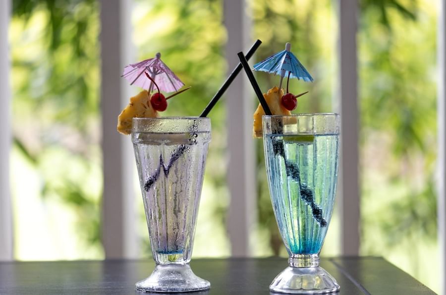 Blue and clear cocktails garnished with pineapple by a straw in Tambua Restaurant at Tambua Sands Beach Resort