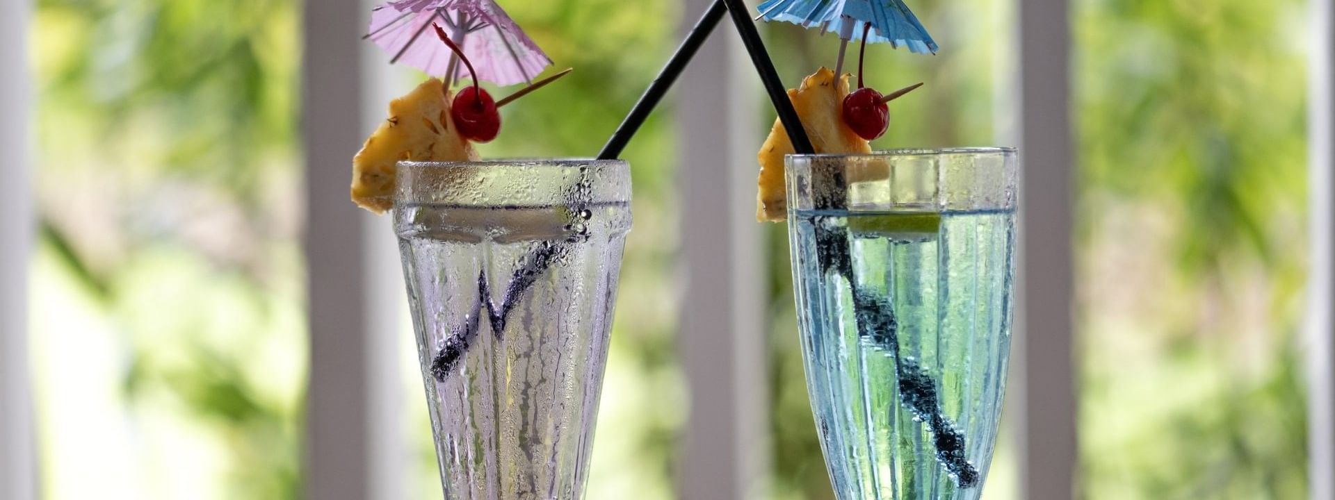 Blue and clear cocktails garnished with pineapple by a straw in Tambua Restaurant at Tambua Sands Beach Resort