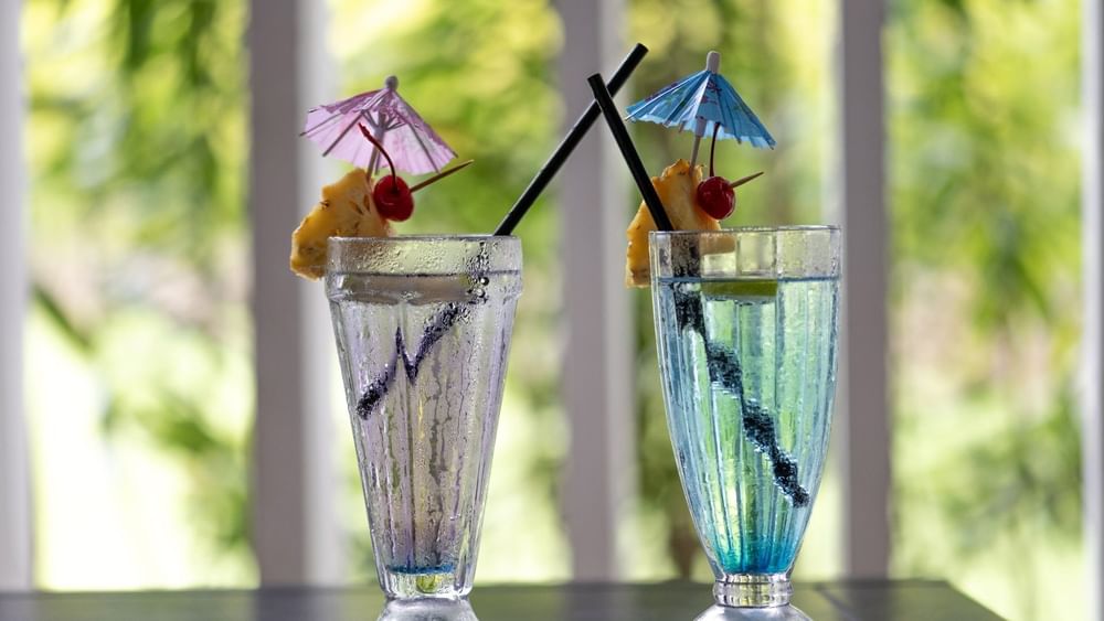 Blue and clear cocktails garnished with pineapple by a straw in Tambua Restaurant at Tambua Sands Beach Resort