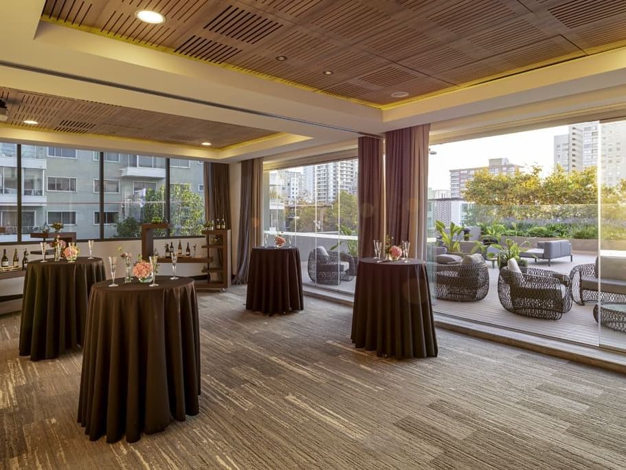 Montaje de cóctel con mesas altas y arreglos florales hacia una terraza en Mistral 3-4, Veranda Hotel