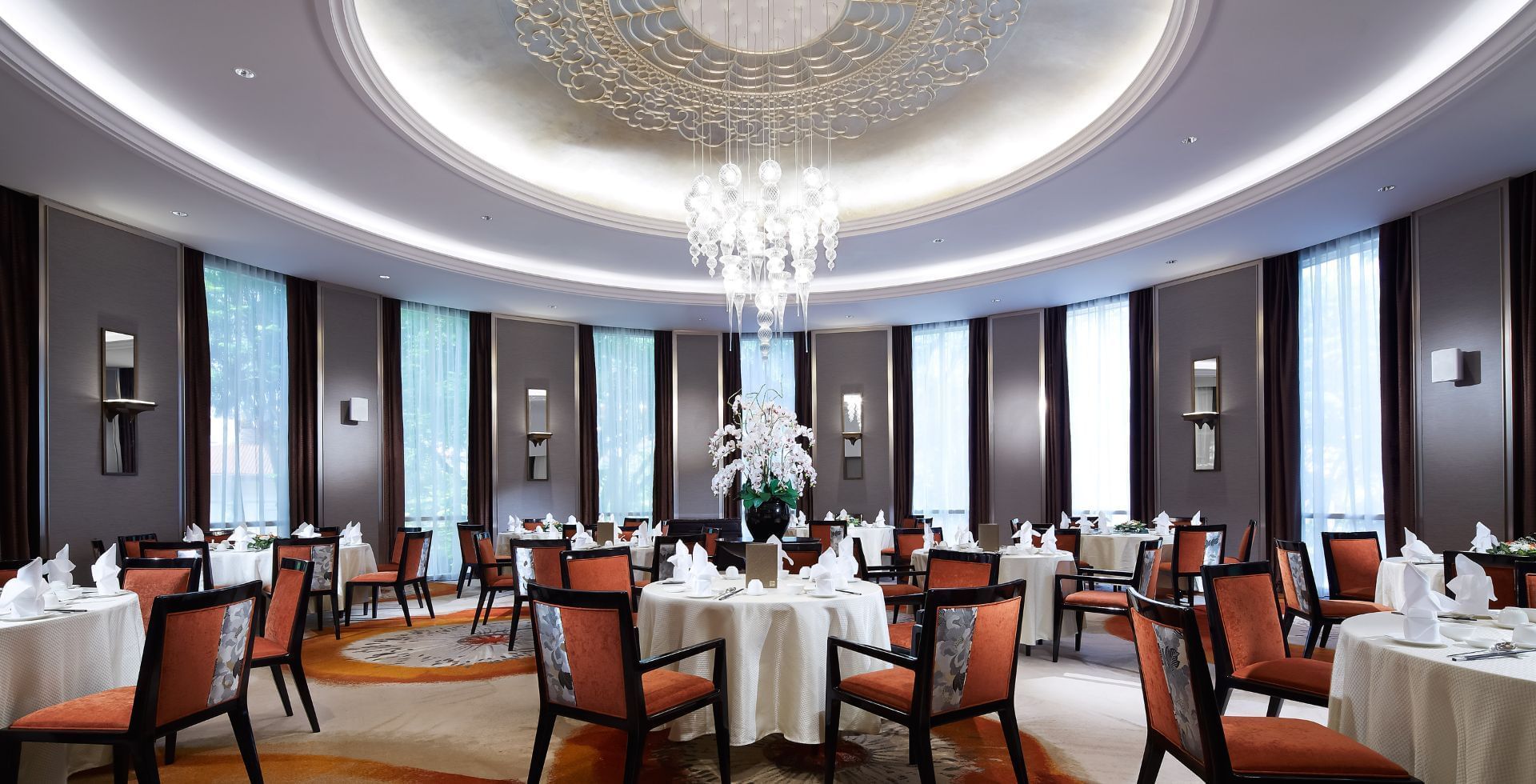 Wah Lok Restaurant with round tables, orange chairs, and a crystal chandelier at Carlton Hotel Singapore
