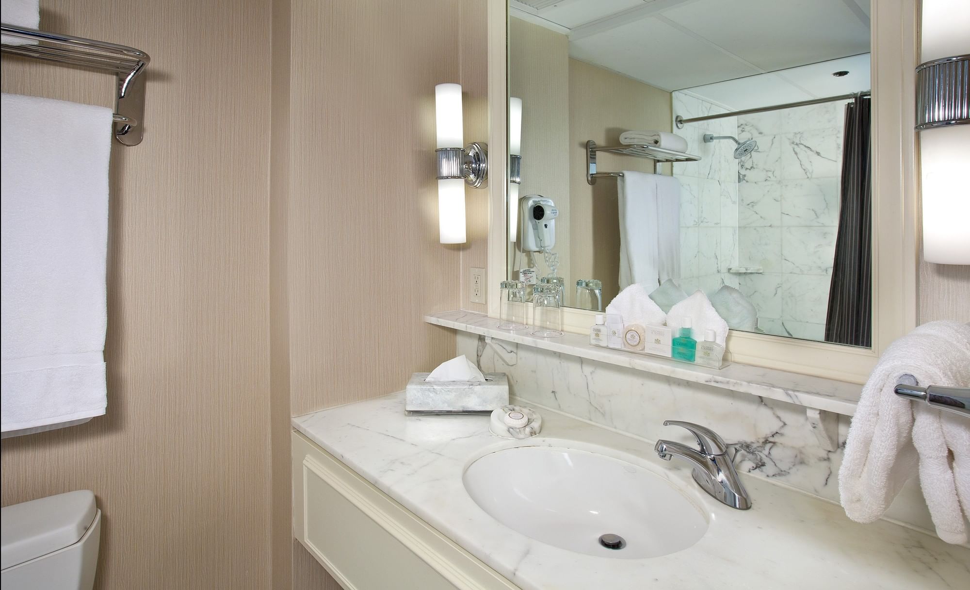 A hotel bathroom with a marble countertop, single sink, and mirror.