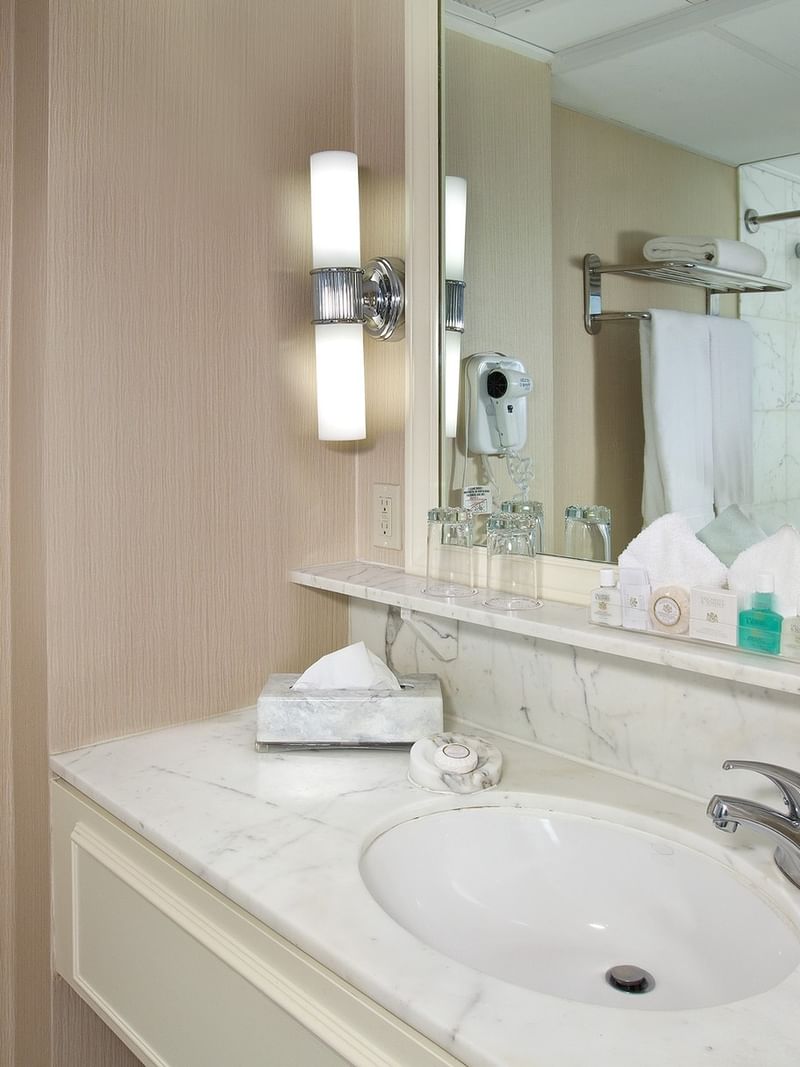 White marble sink featuring travel toiletries by a bright wall lamp in Classic Room at Warwick Seattle
