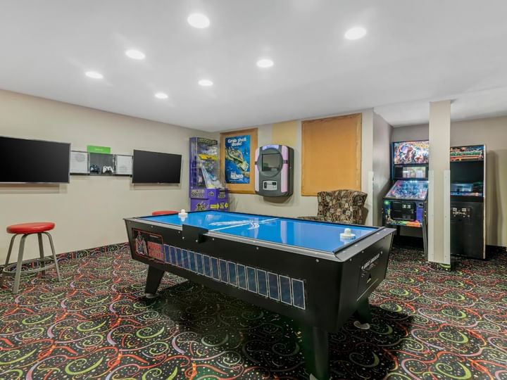 A game room with a pool table, arcade games, and a TV.