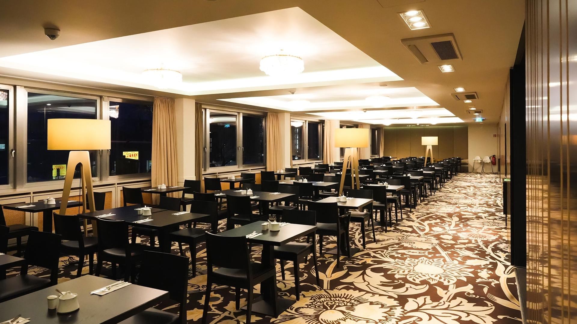 Elegantes Frühstücksrestaurant mit großen Fenstern und stilvollen Möbeln im Sylter Hof Berlin.