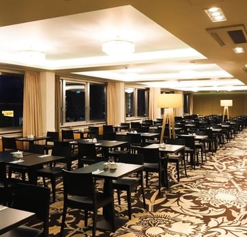 Elegantes Frühstücksrestaurant mit großen Fenstern und stilvollen Möbeln im Sylter Hof Berlin.